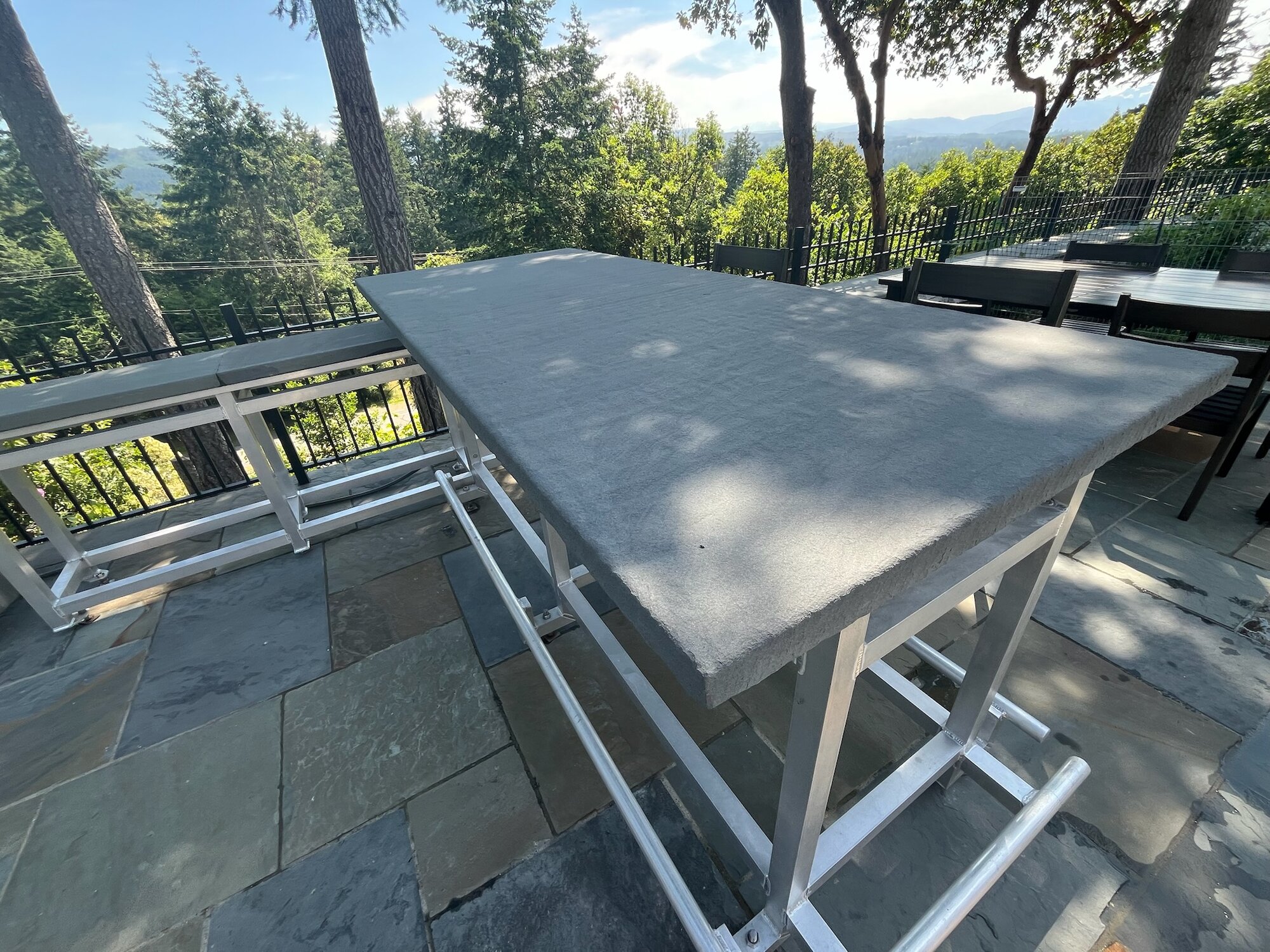 Custom granite outdoor dining table on a flagstone patio with mountain view