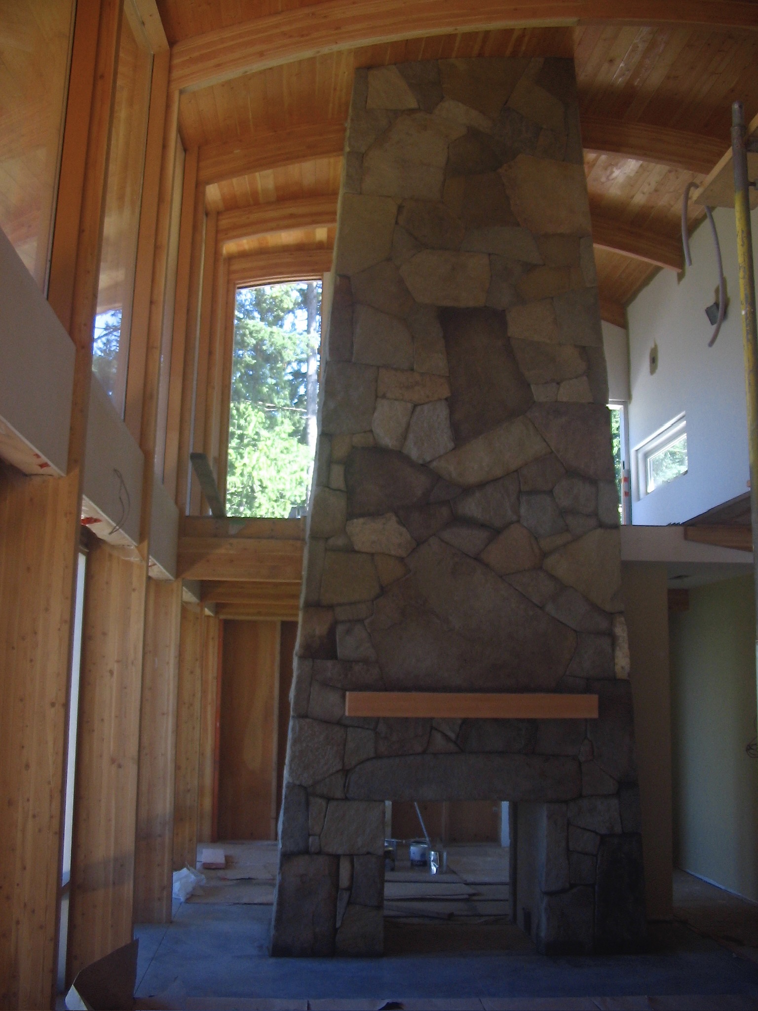 Tall flagstone fireplace beneath a curved wood ceiling