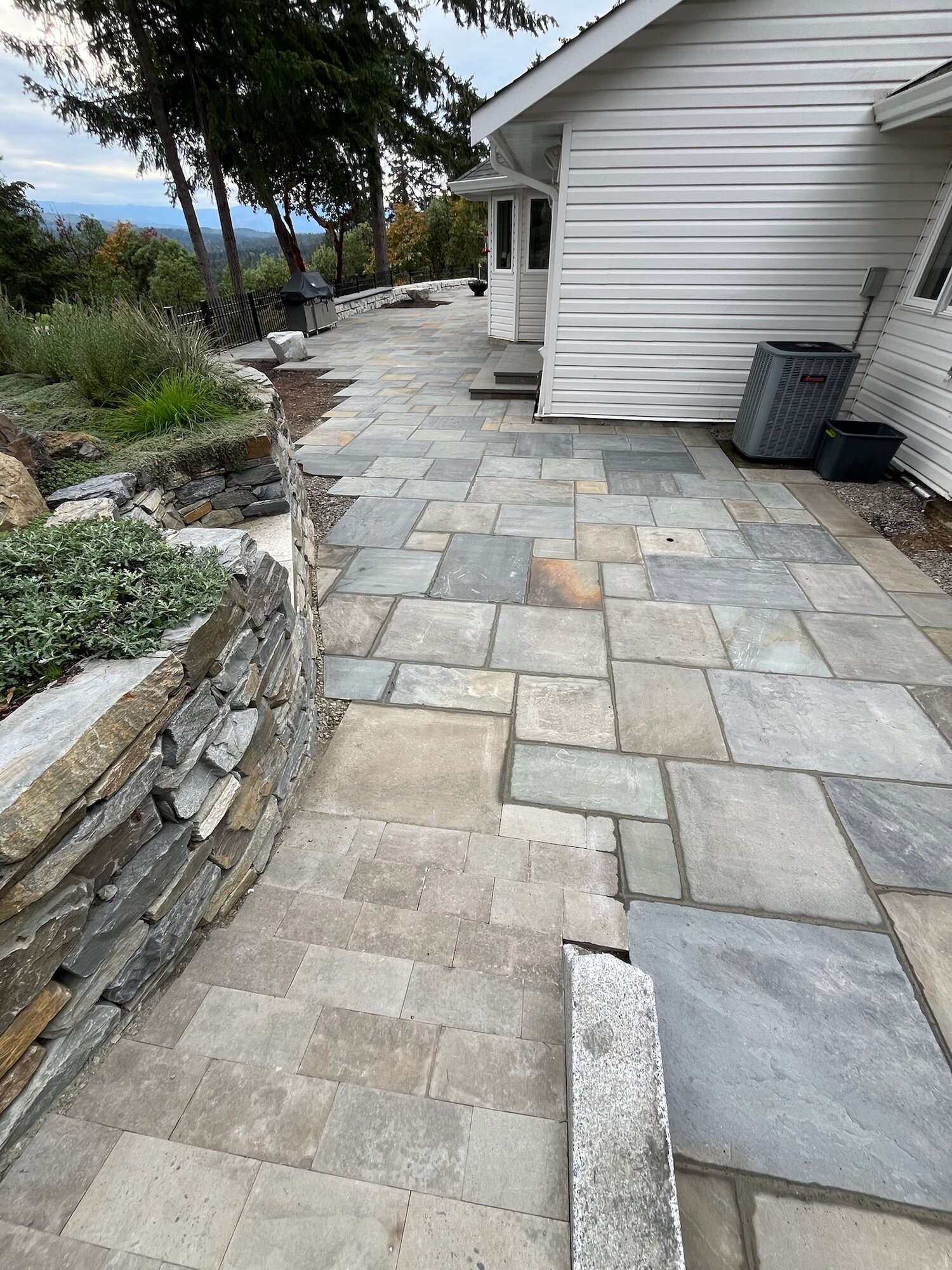 Wide flagstone walkway alongside a dry-stack wall with a mountain view