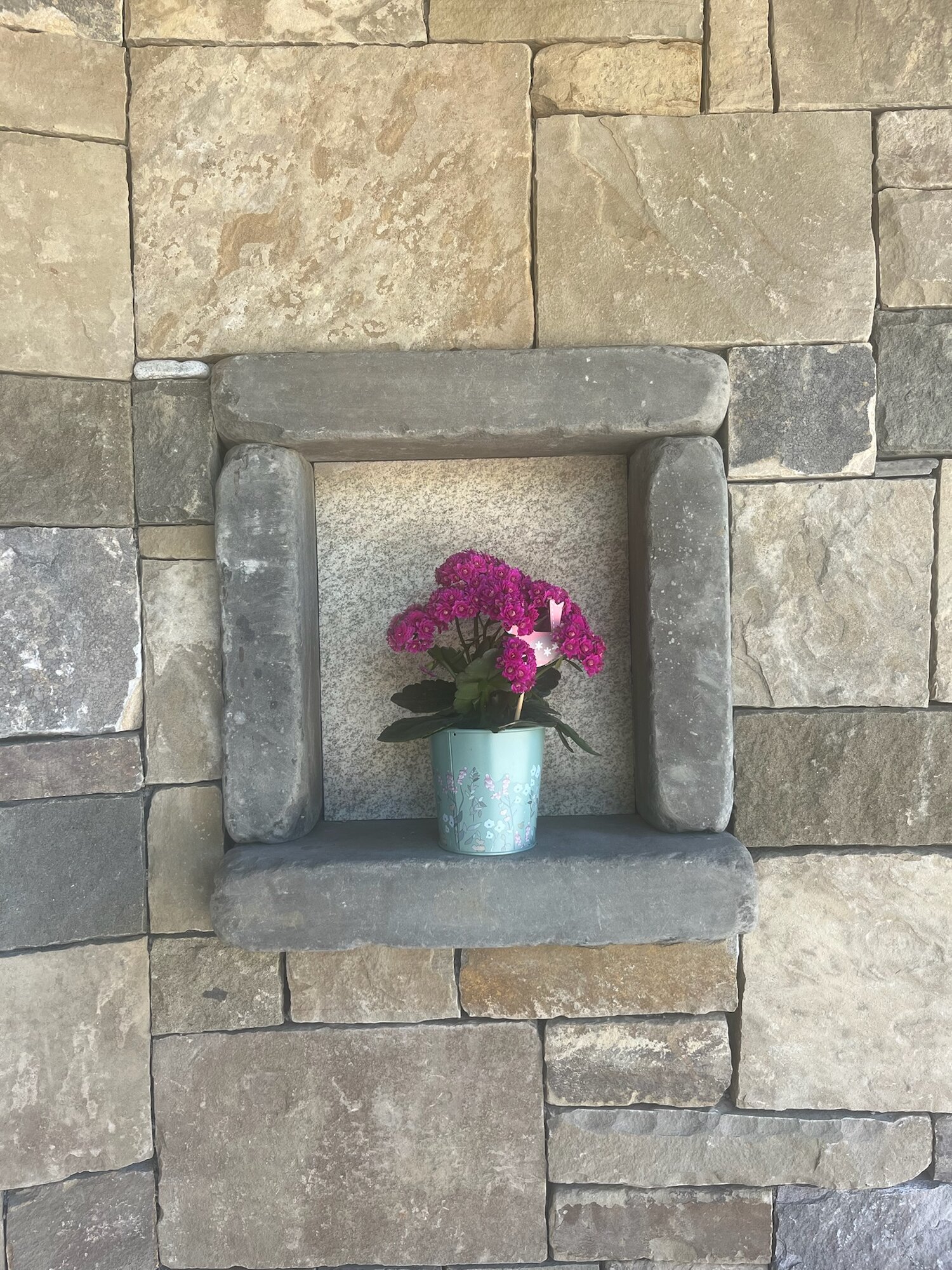 Stone wall with a custom carved niche and granite surround, flower pot inside